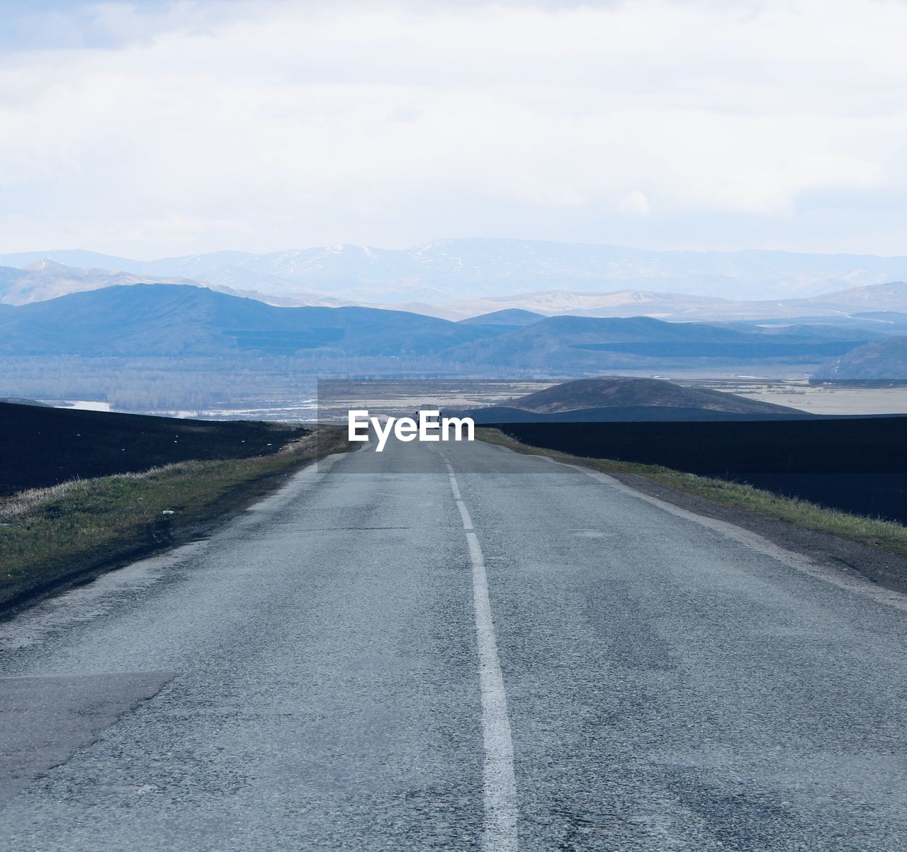 Empty road along landscape and mountains against sky