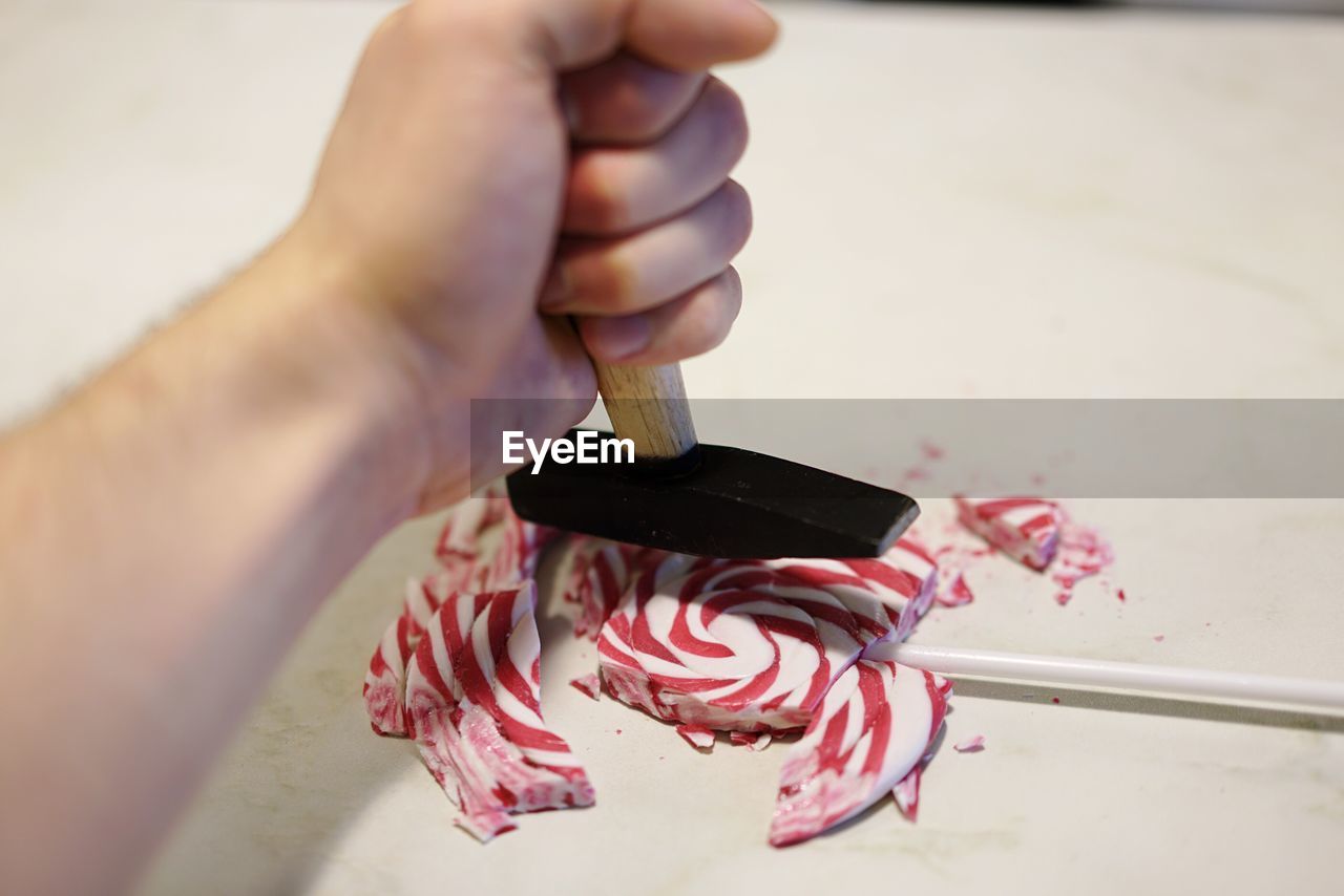 Close-up of hand crushing lollipop