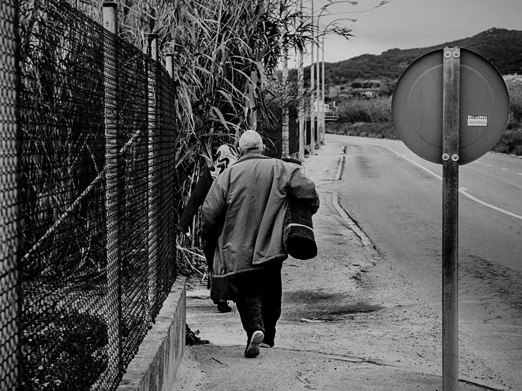 REAR VIEW OF MAN STANDING ON BENCH