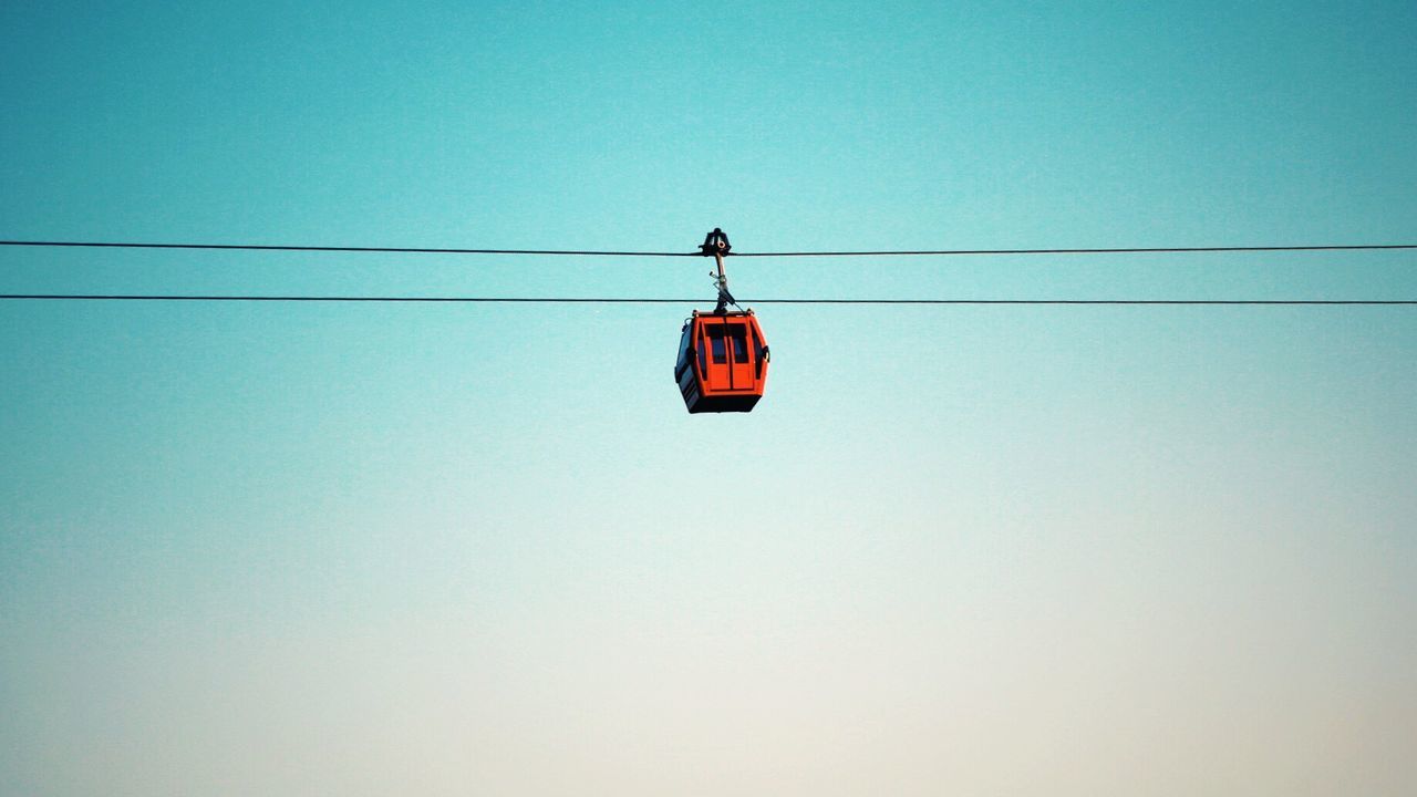 LOW ANGLE VIEW OF OVERHEAD CABLE CARS AGAINST CLEAR SKY