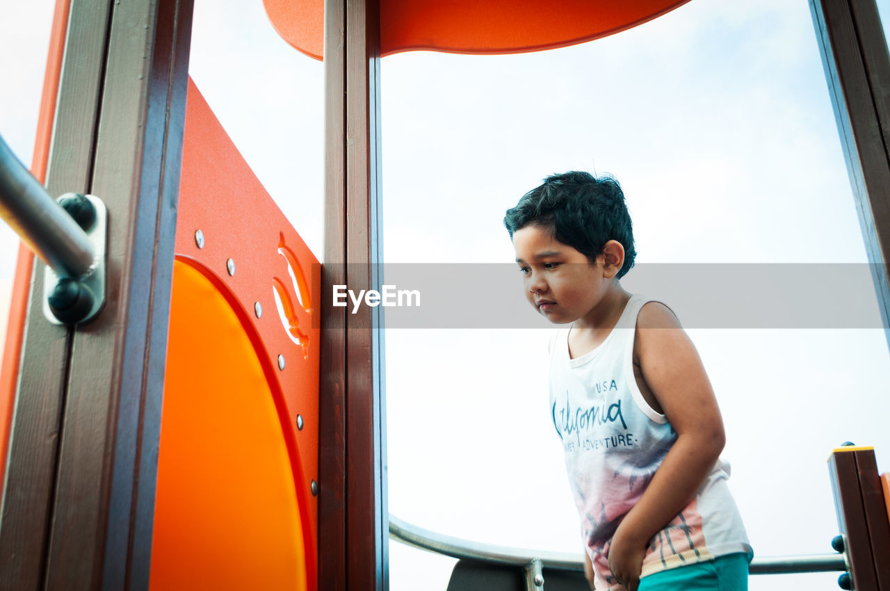 Cute boy playing on outdoor play equipment