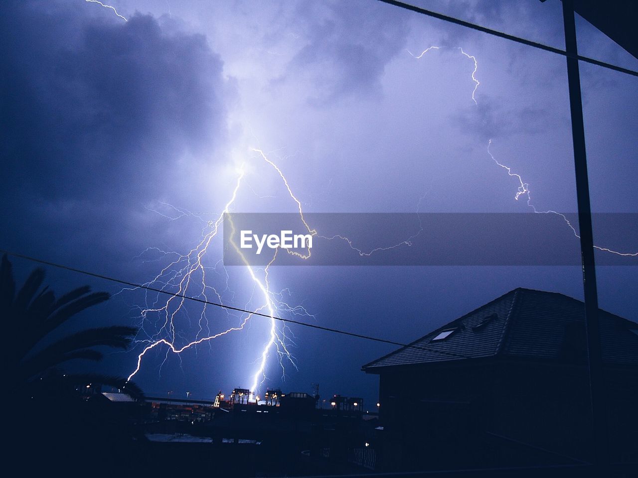 Low angle view of thunderstorm over residential district at night