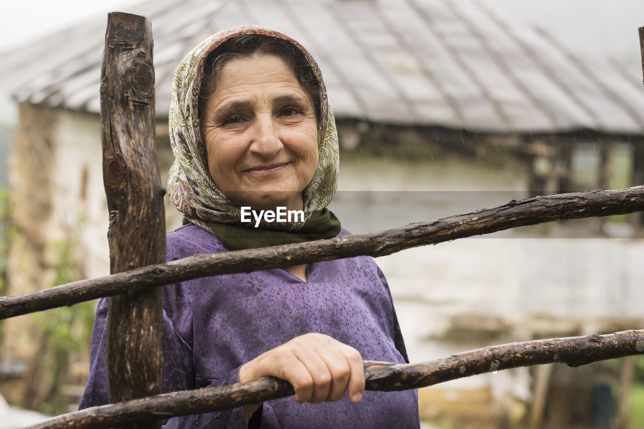 Portrait of senior woman standing by fence