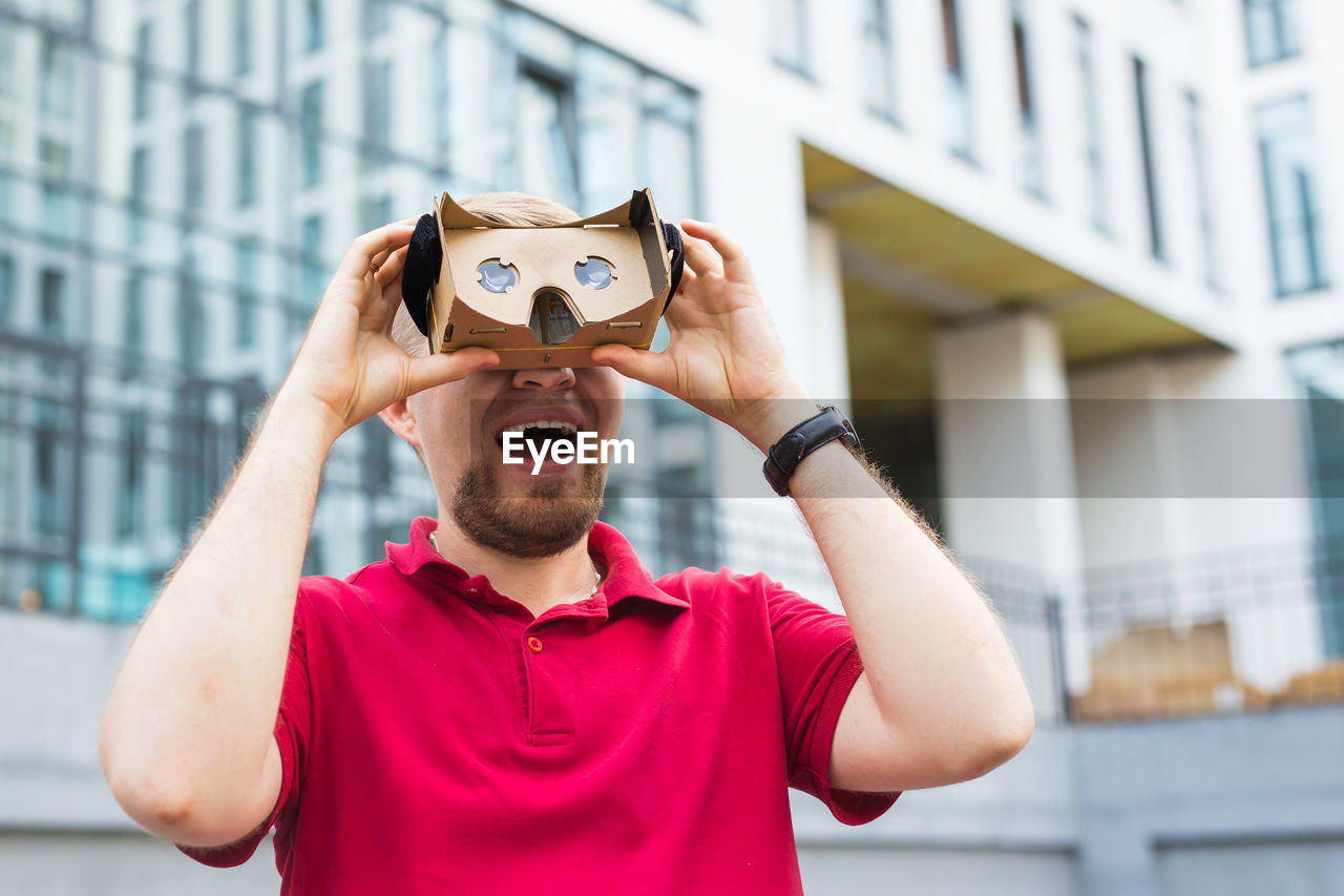 Man wearing virtual reality headset while standing against built structure