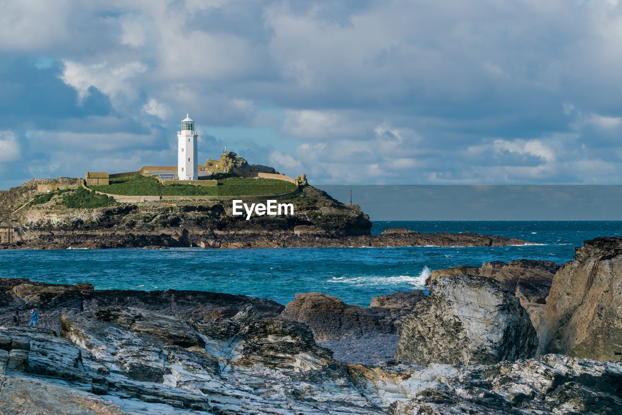 Lighthouse by sea against sky