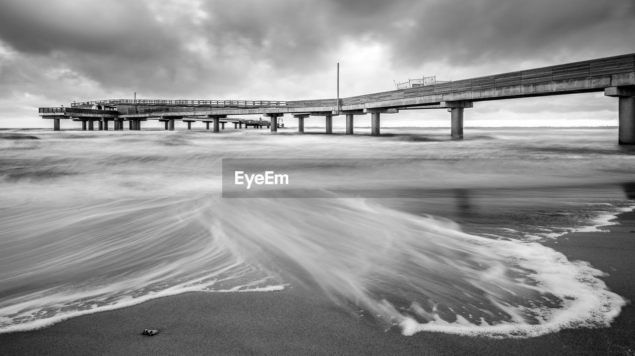 BRIDGE OVER BEACH AGAINST SKY