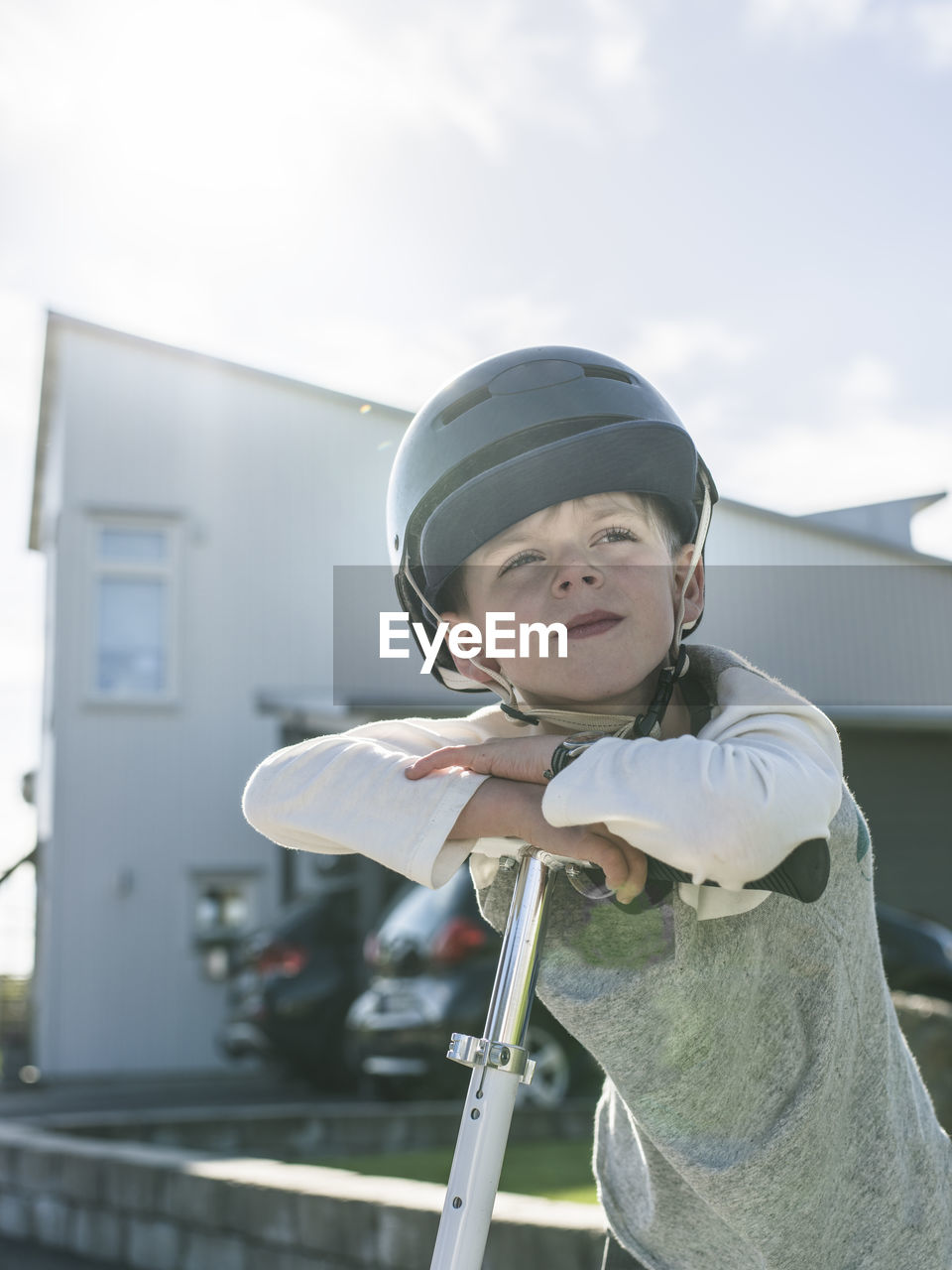 Boy in bicycle helmet standing with kick scooter