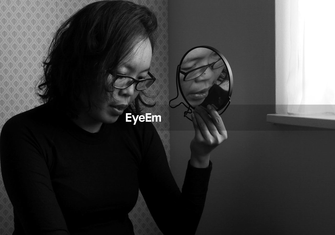 Woman with reflection in mirror sitting at home