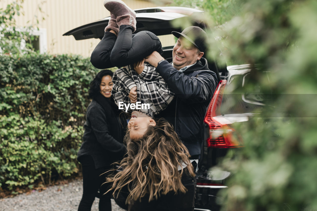 Playful father lifting daughter upside down