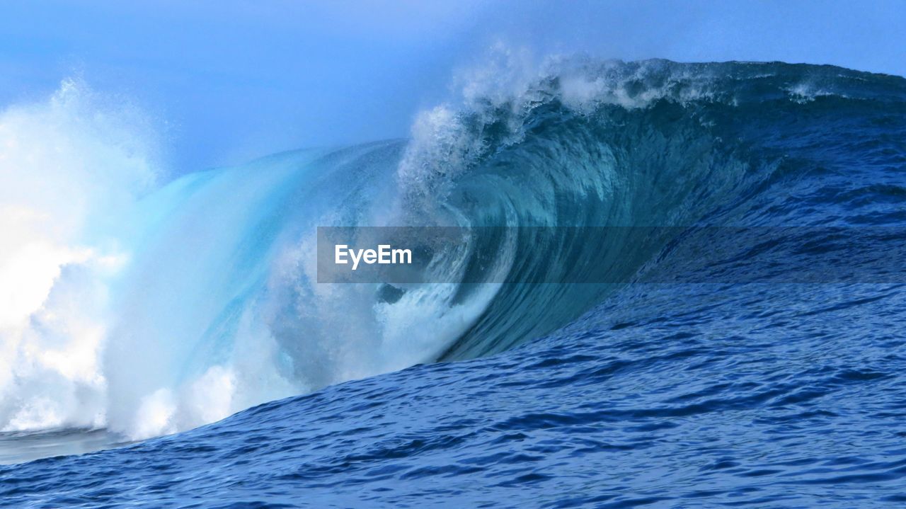 Scenic view of sea waves splashing against blue sky