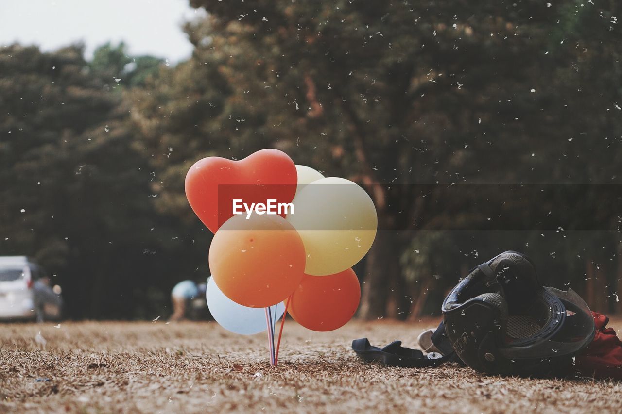 Multi colored balloons by helmet on field