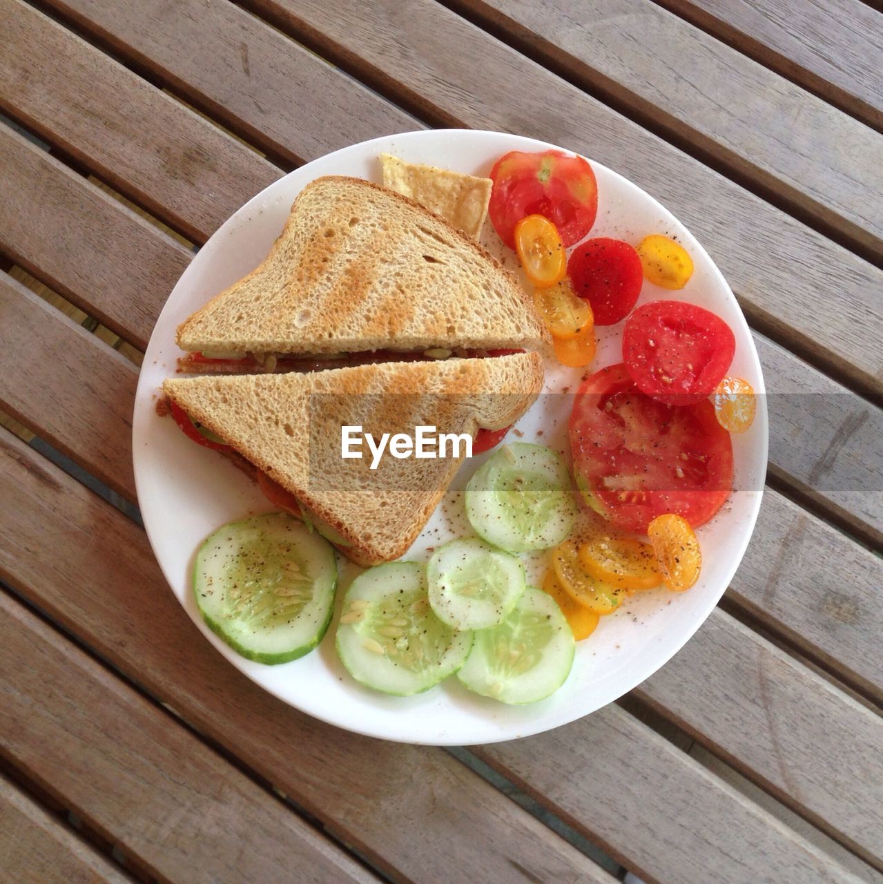 Directly above shot of sandwich served with tomatoes and cucumber