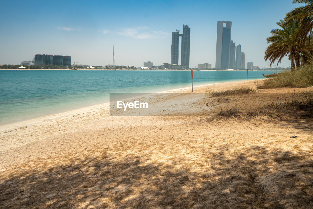 Sea by buildings against sky in city in abu dhabi