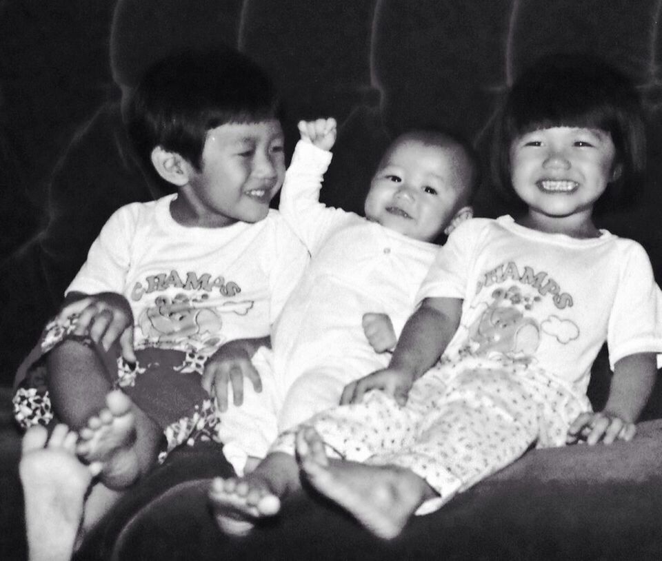 Close-up of three children sitting on a sofa and smiling