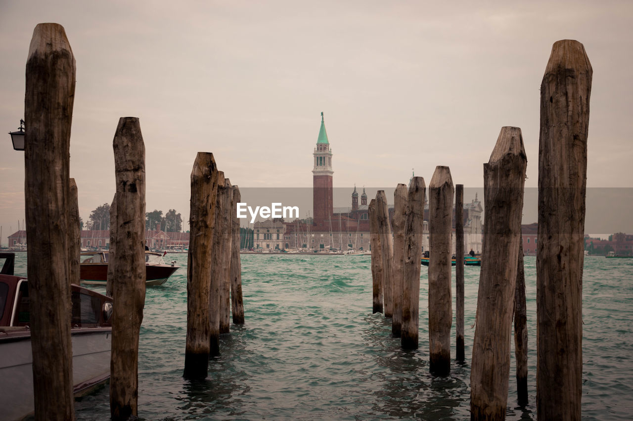 Panoramic view of sea, wooden pillars and buildings 