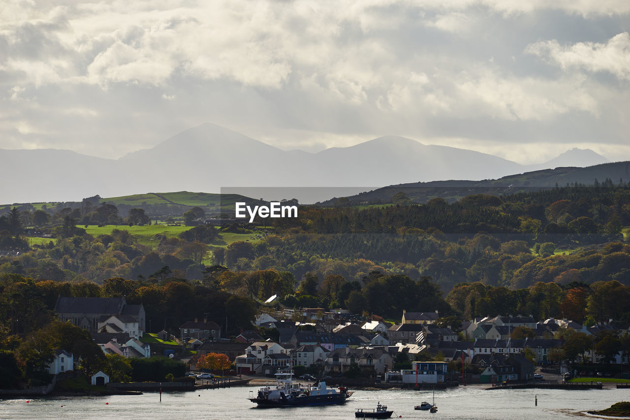 Sea by city against mountains