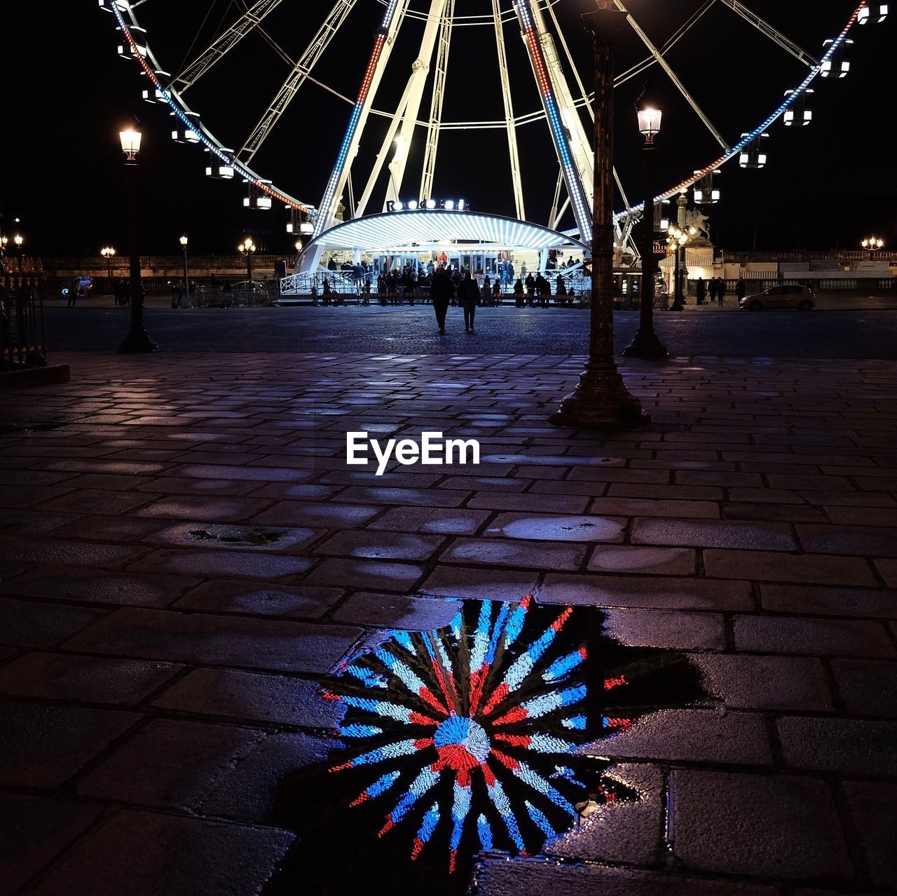 LOW ANGLE VIEW OF ILLUMINATED FERRIS WHEEL IN CITY AT NIGHT