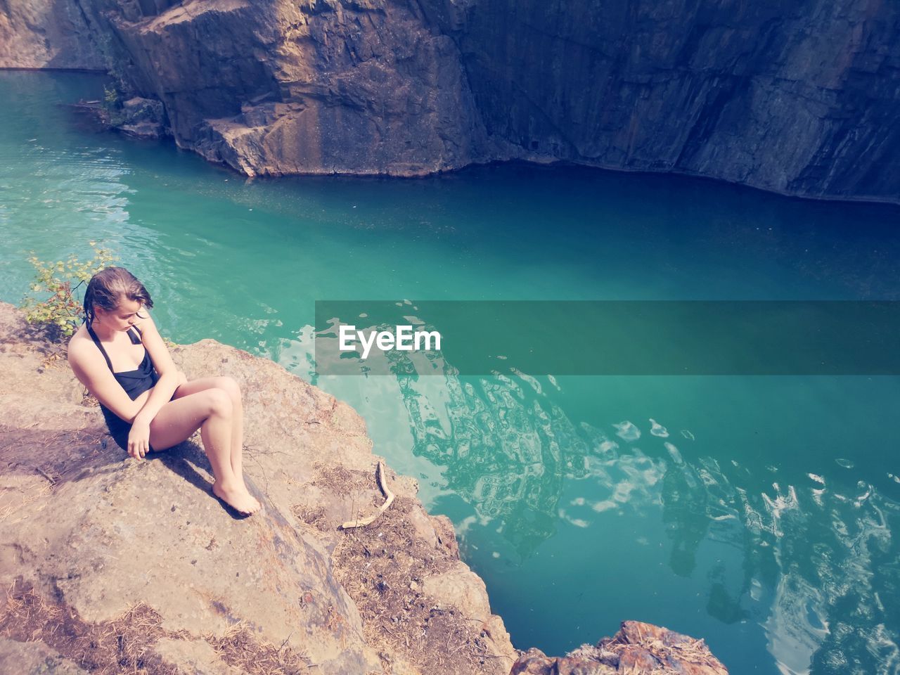 Girl sitting on rock by sea