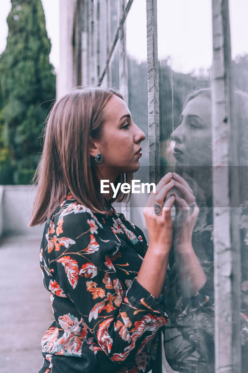 Side view of young woman looking through window