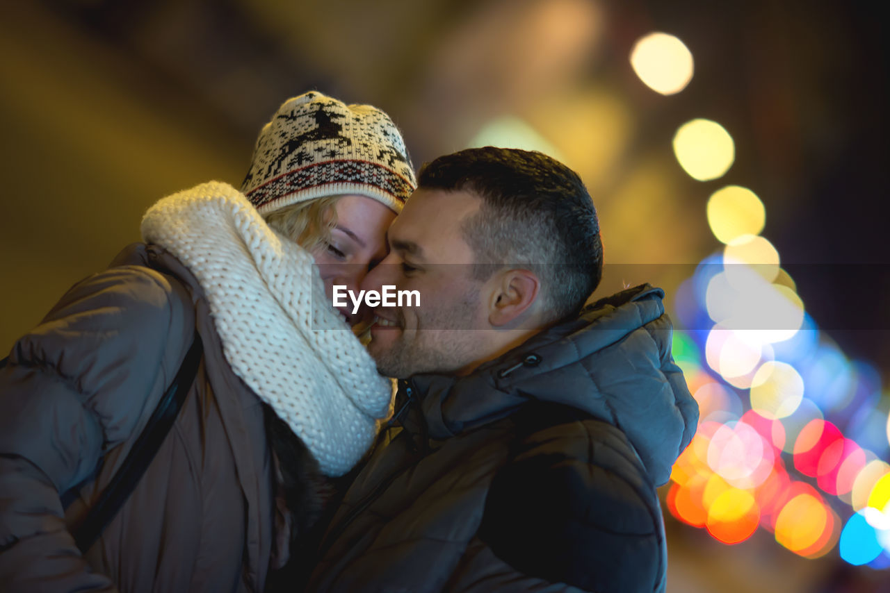 Smiling young couple standing at night during winter