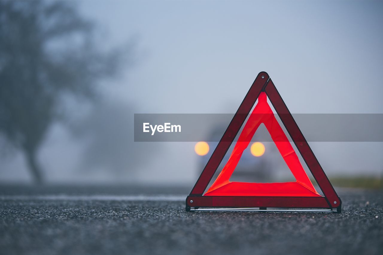 Close-up of red yield sign on road in city during foggy weather