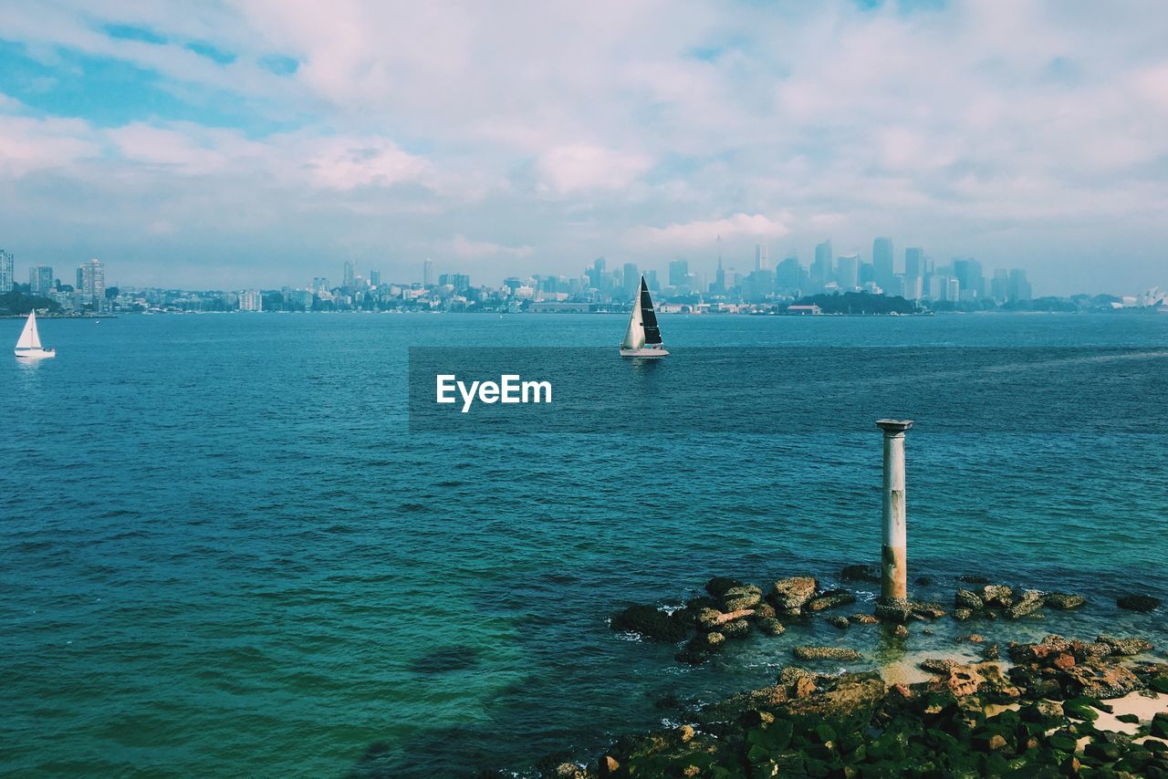 Boats in sea against cloudy sky