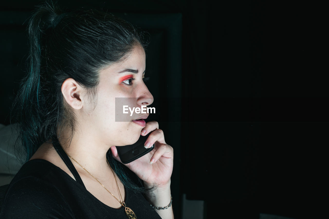 one person, adult, singing, women, portrait, headshot, young adult, black, indoors, person, copy space, human face, looking, looking away, lifestyles, hairstyle, arts culture and entertainment, lipstick, technology, emotion, female, make-up, black hair, contemplation, fashion, communication, black background