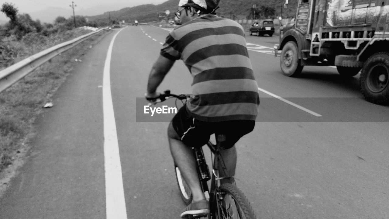 MAN RIDING BICYCLE ON ROAD