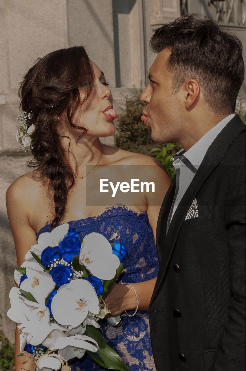 Bride and groom sticking out tongues while looking at each other