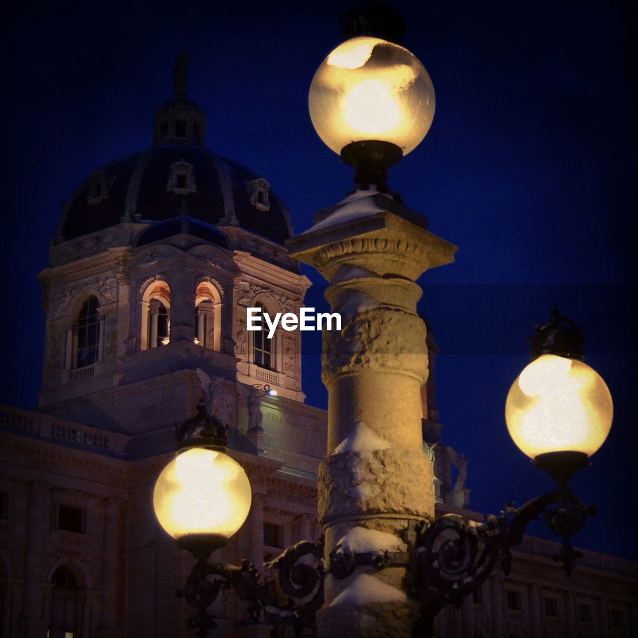 Illuminated street light outside building against sky at night