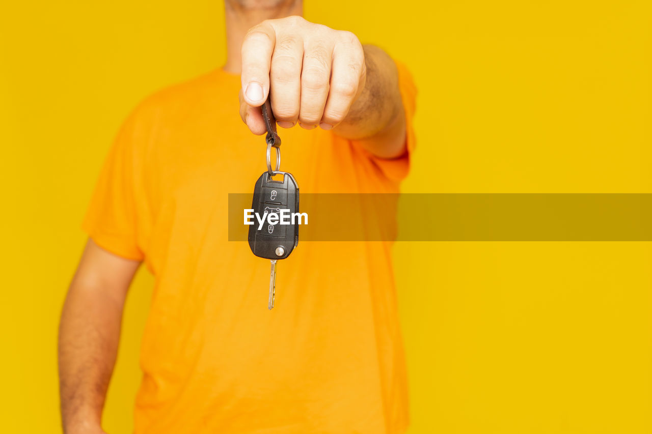 yellow, studio shot, colored background, orange, one person, yellow background, t-shirt, adult, hand, indoors, orange color, clothing, holding, front view, finger, person, men, casual clothing, copy space