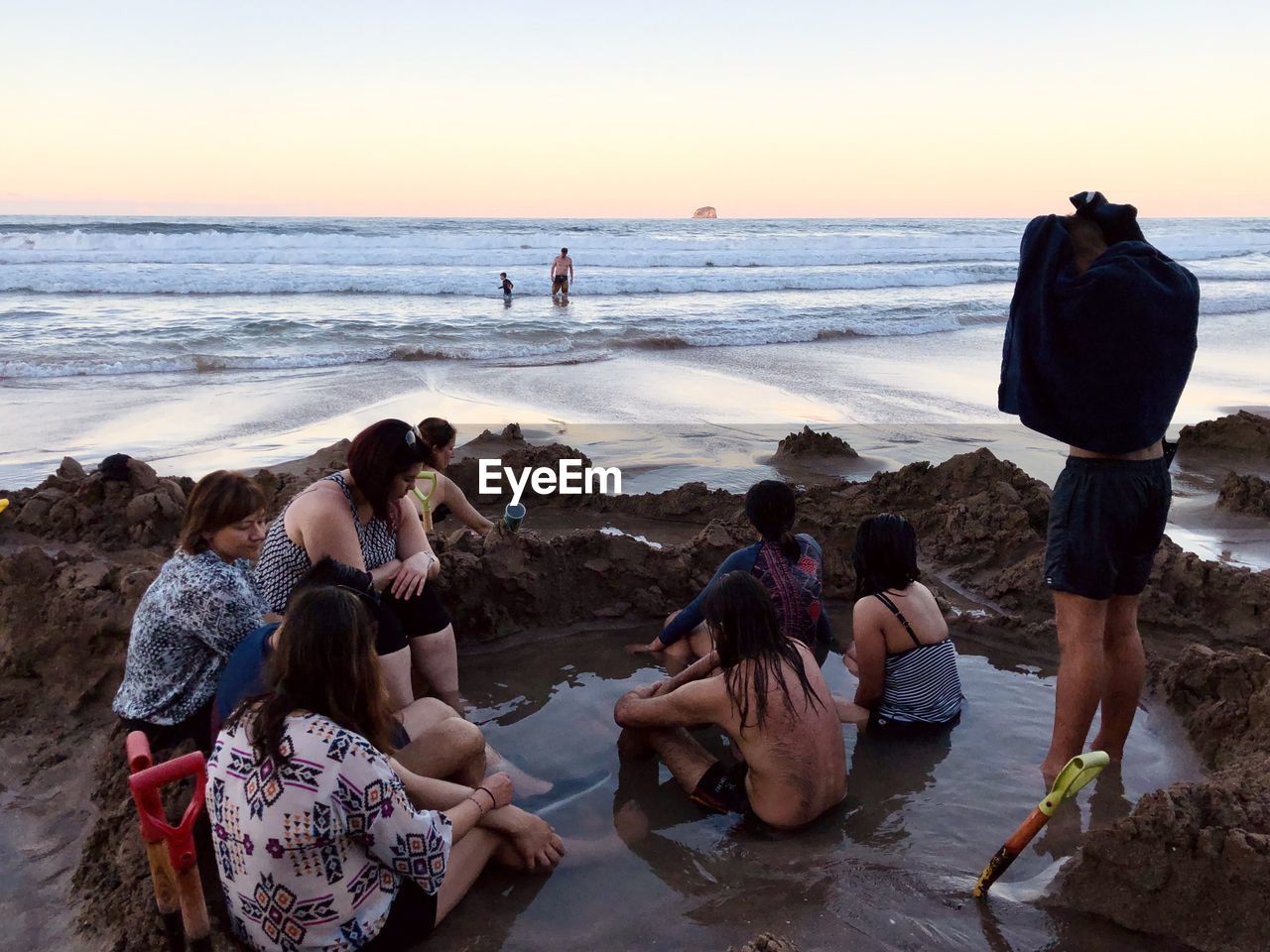 PEOPLE ON BEACH AGAINST SEA