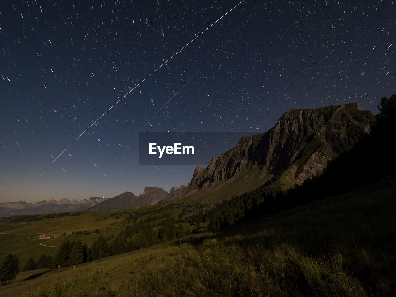 Scenic view of moonlit mountains against starry night sky 