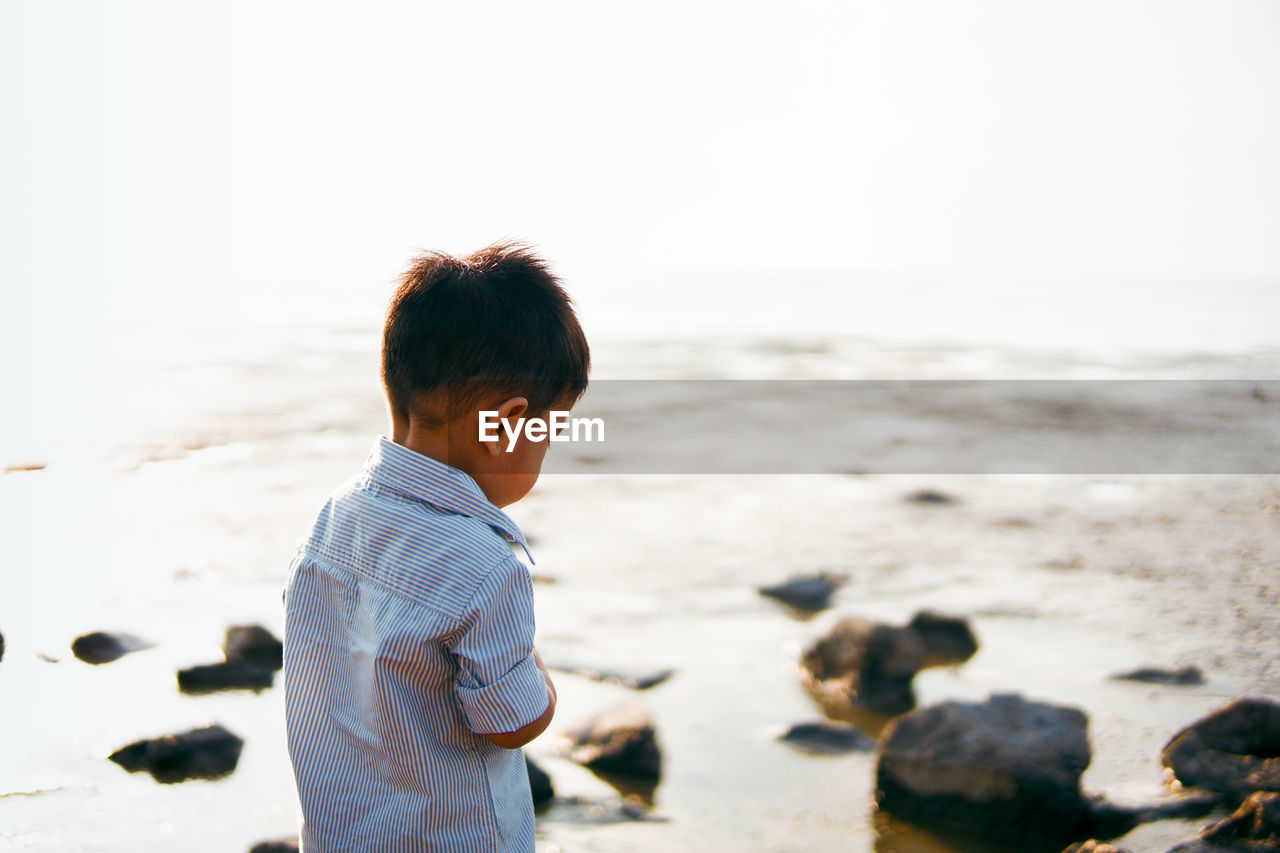 BOY ON BEACH AGAINST SEA