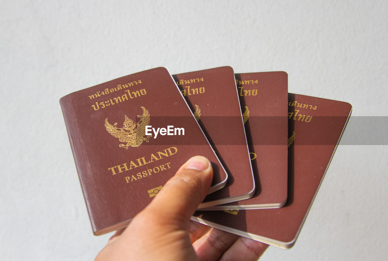 Cropped hand holding passports against wall