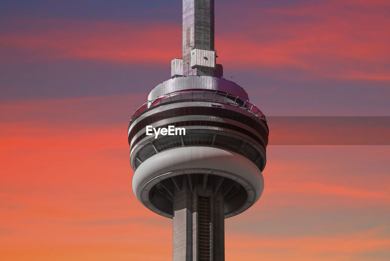 LOW ANGLE VIEW OF COMMUNICATIONS TOWER AGAINST ORANGE SKY