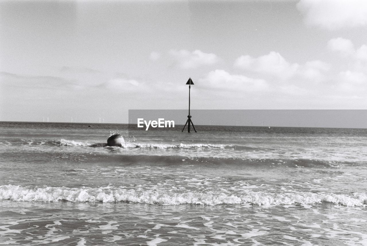 Man swimming in sea against sky