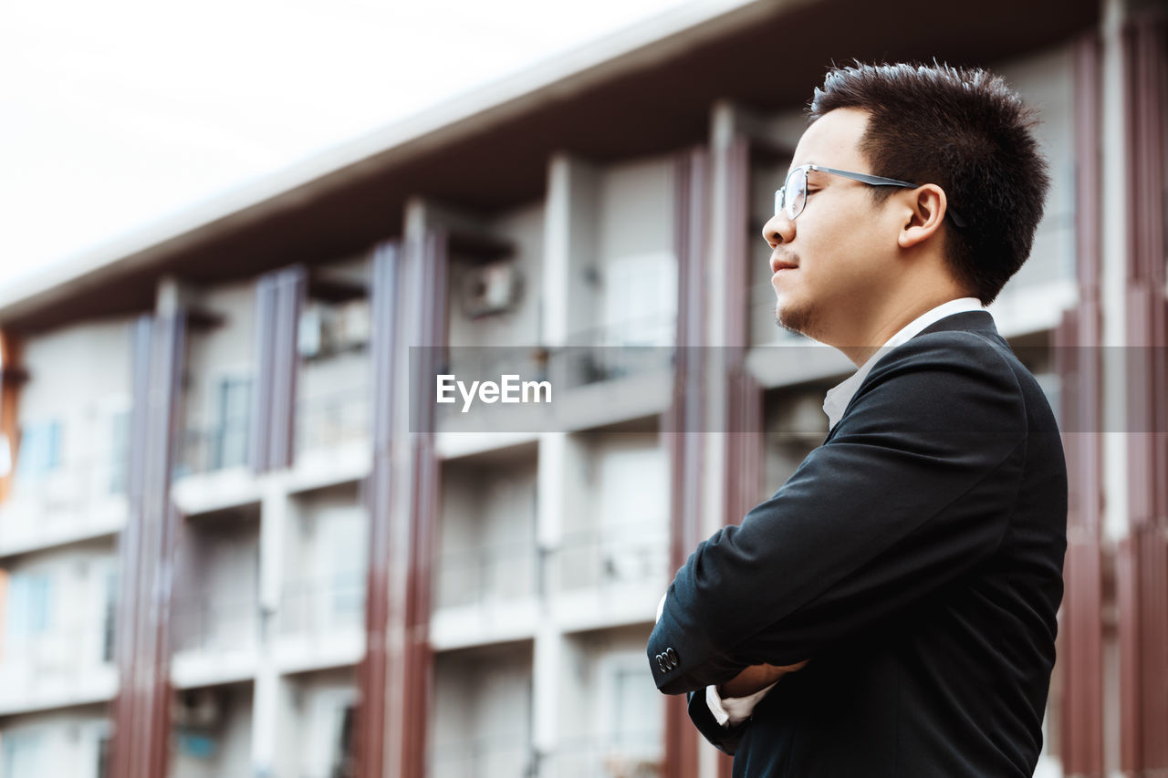 Side view of man looking away against building