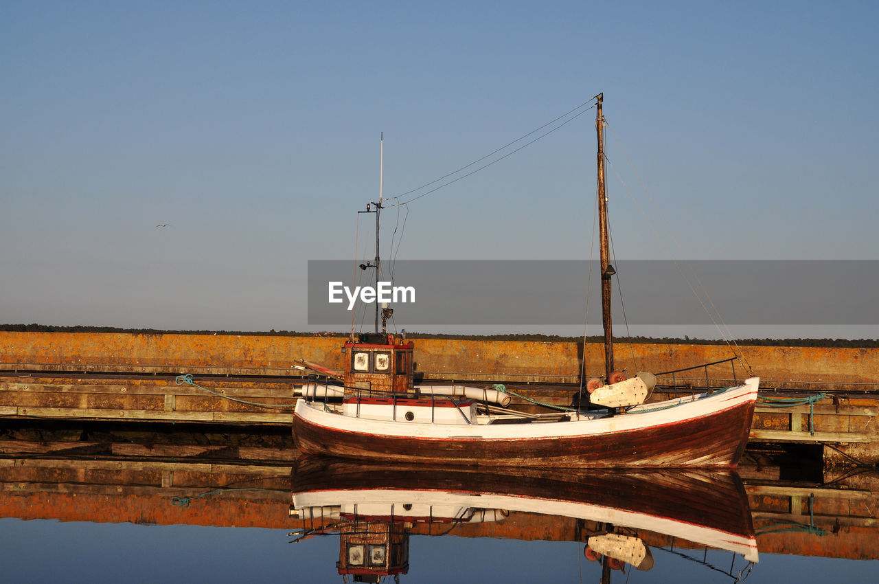 Ship moored on shore against clear sky