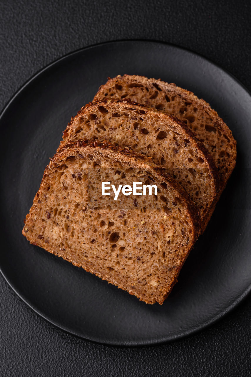 food and drink, food, rye bread, bread, brown bread, wellbeing, healthy eating, freshness, indoors, studio shot, baked, slice, no people, black background, close-up, brown, whole grain, pumpkin bread, produce, loaf of bread, simplicity, directly above, wheat, still life