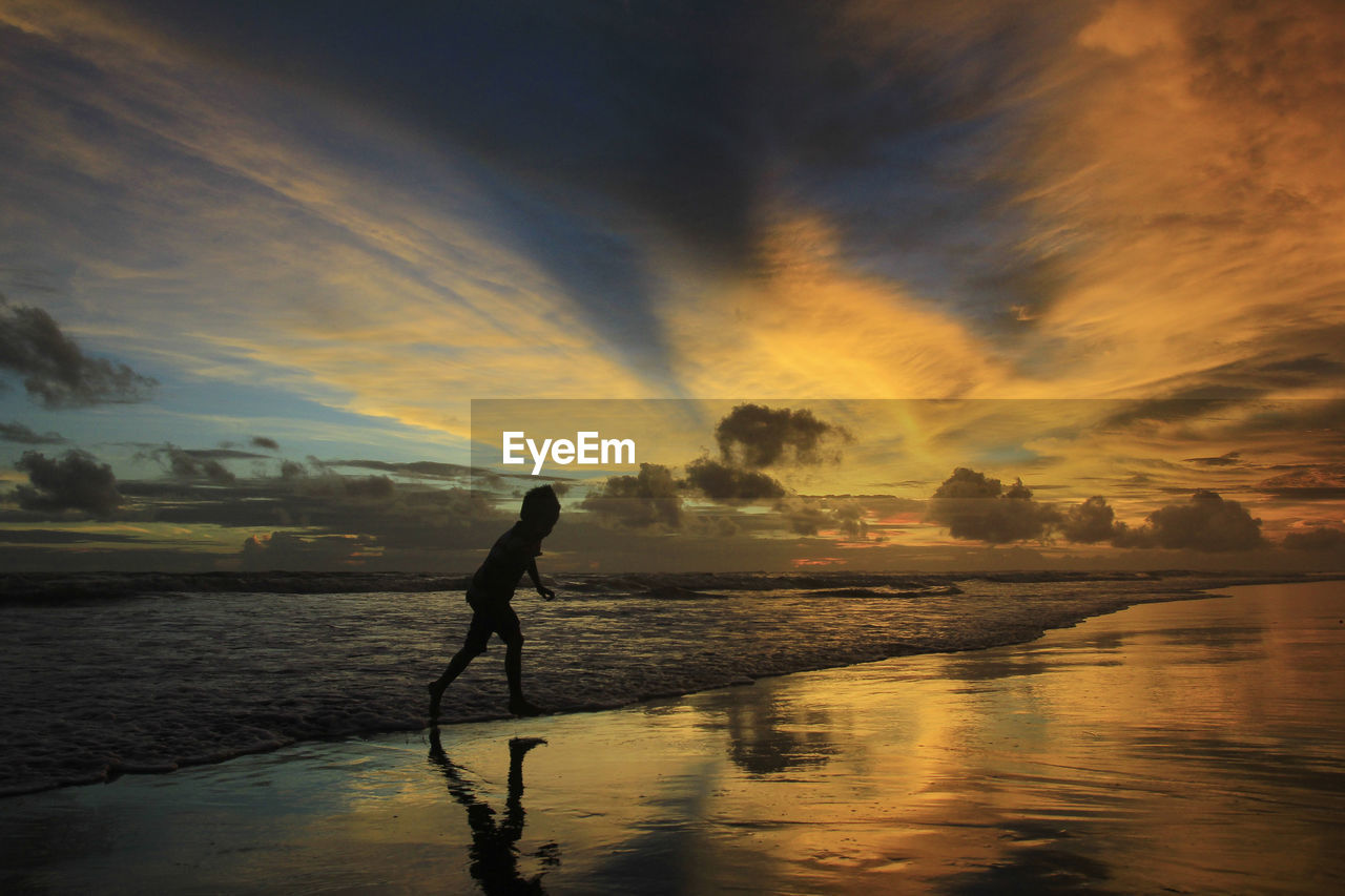 SILHOUETTE MAN ON SHORE AGAINST SKY DURING SUNSET