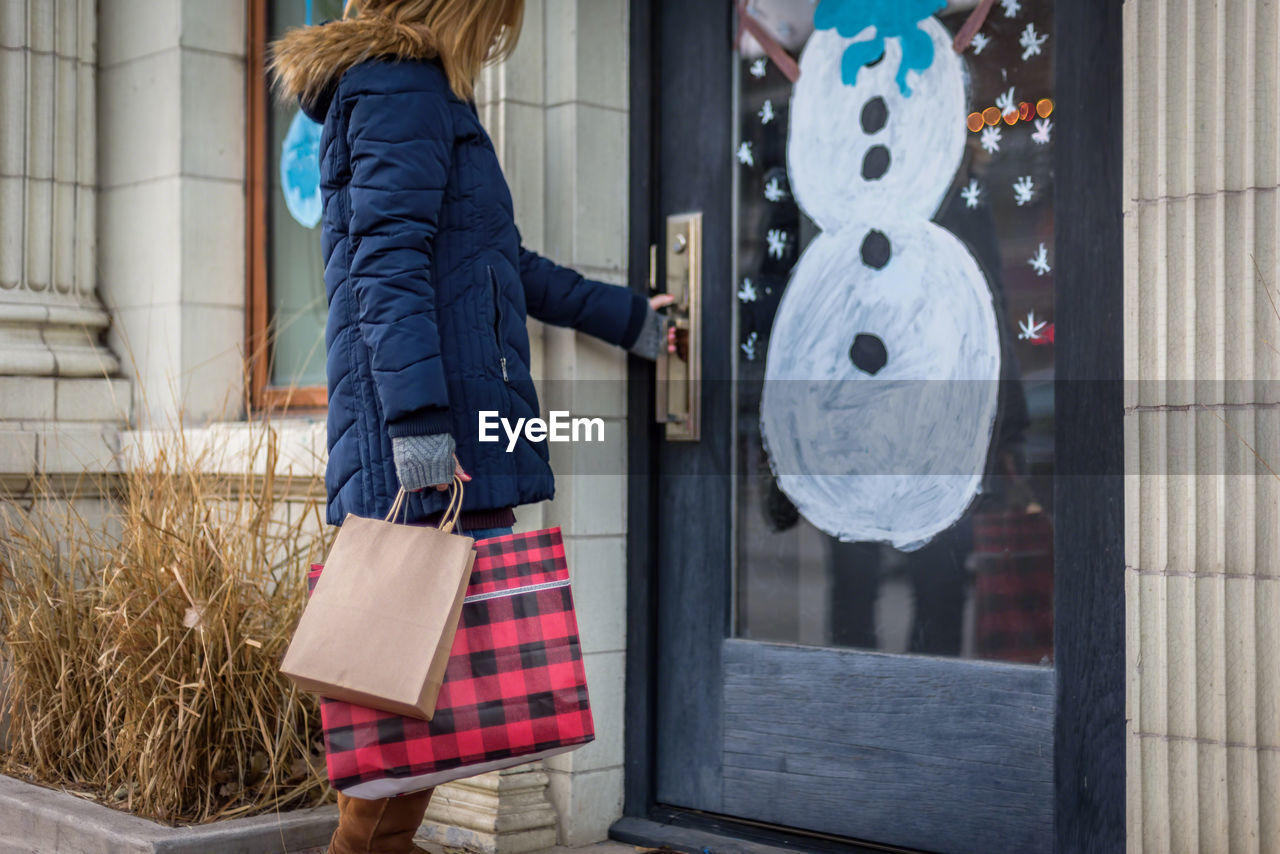 Woman with shopping bags standing on doorway