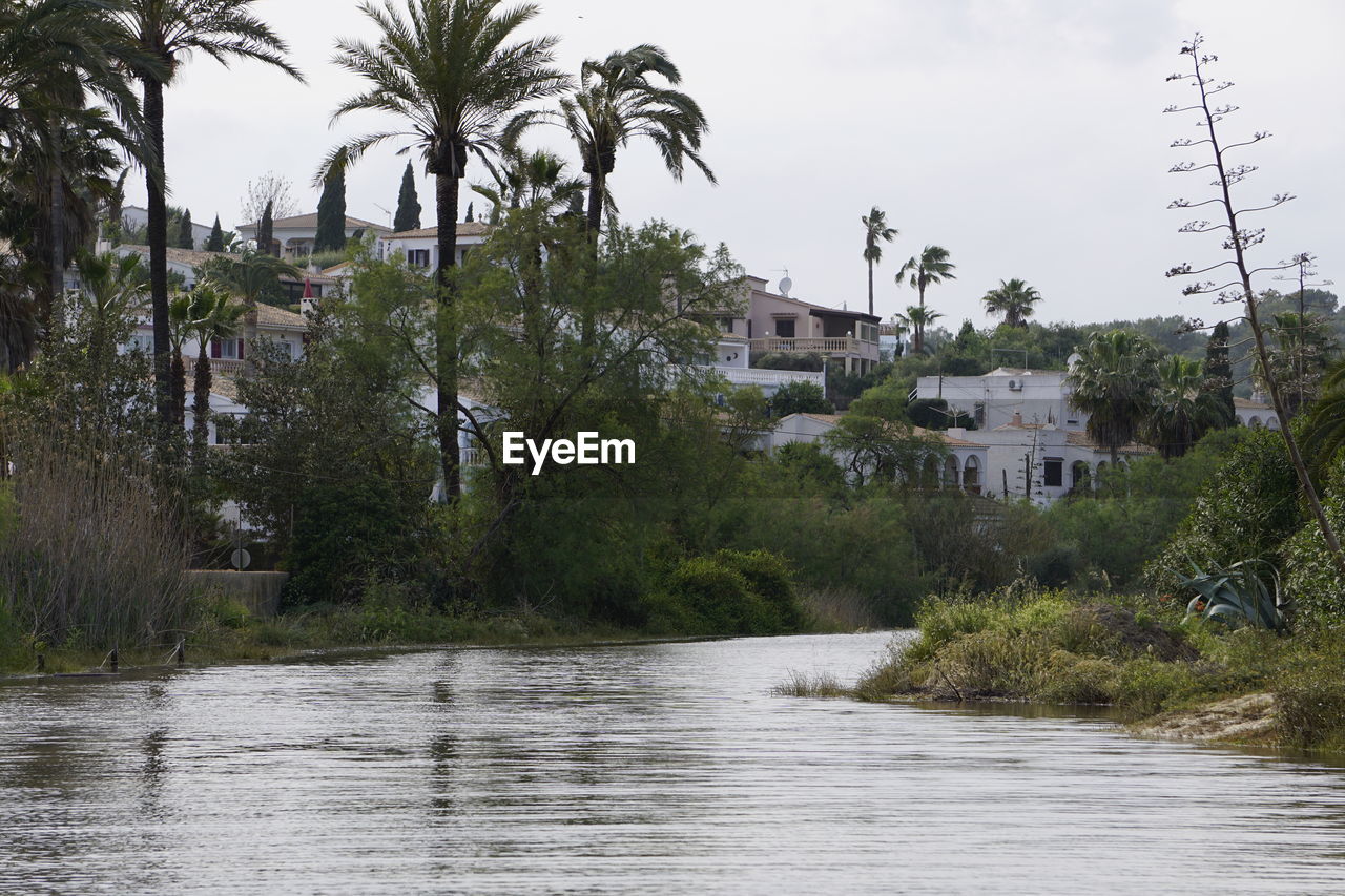 River amidst trees and houses against sky