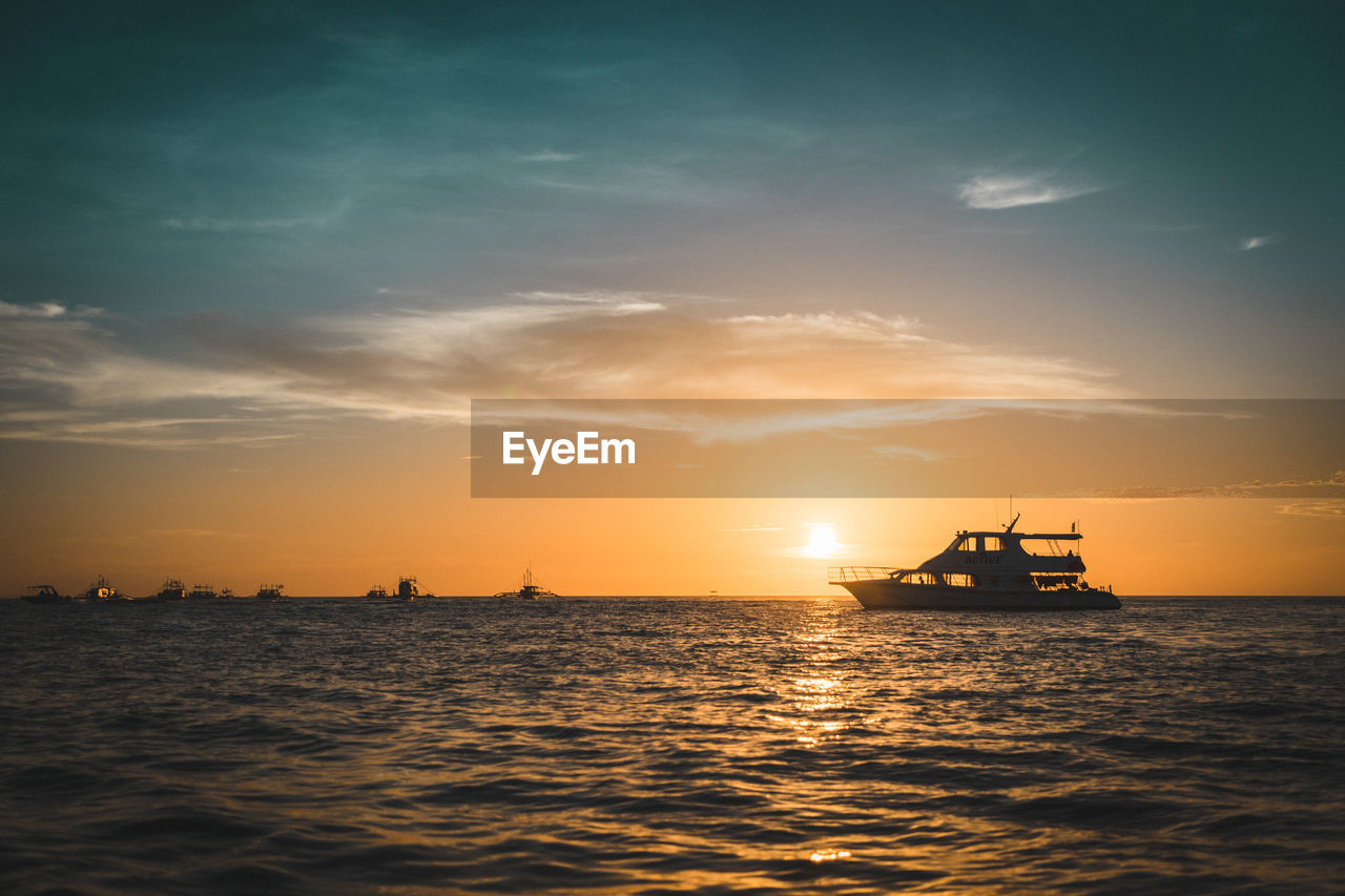 Silhouette sailboat in sea against sky during sunset