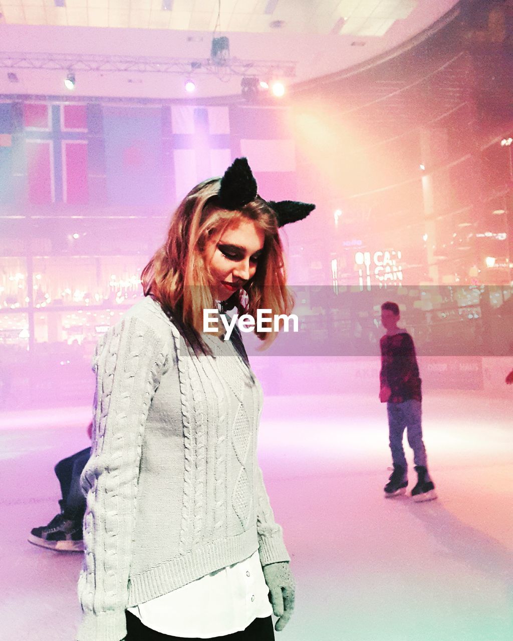 Young woman wearing costume ears and sweater while standing at ice rink