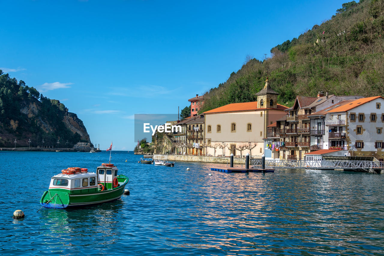 Boat in sea by buildings against sky