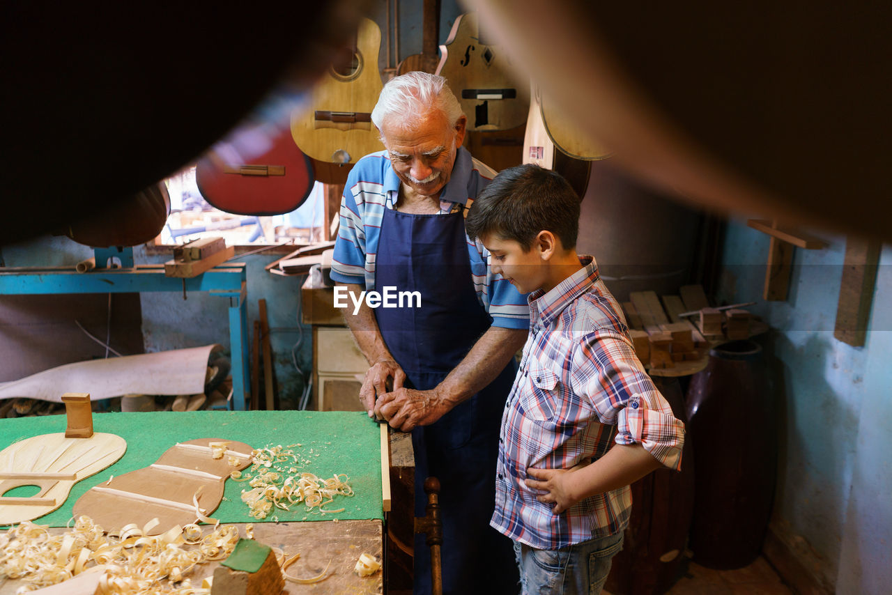 High angle view of senior man teaching instrument making to boy in workshop