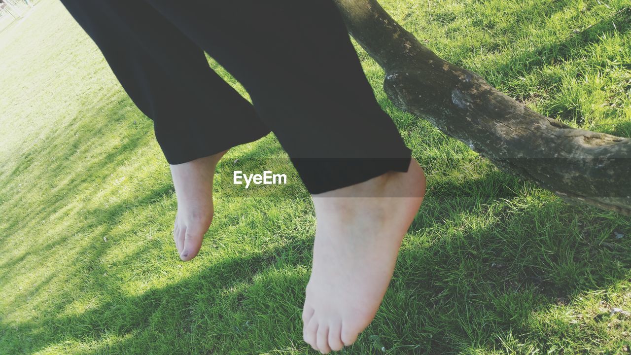 Close-up low section of bare feet against grass