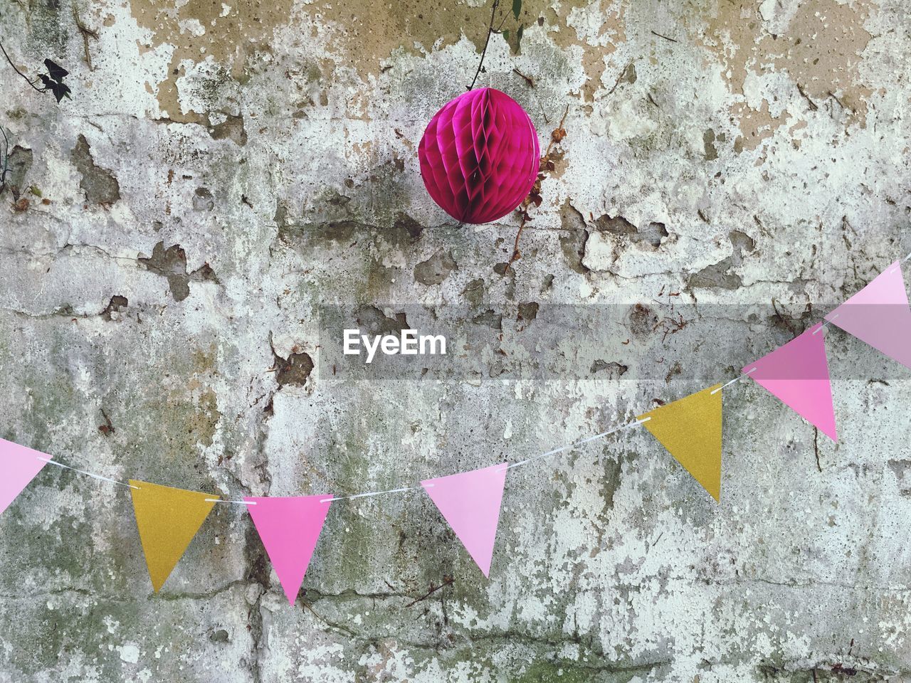 Multi colored decoration hanging against weathered wall