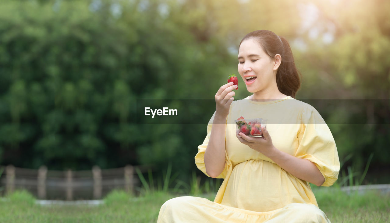 YOUNG WOMAN SITTING ON FIELD WITH PLANTS